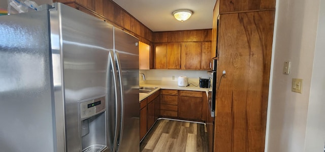 kitchen featuring dark wood-style flooring, a sink, light countertops, stainless steel refrigerator with ice dispenser, and brown cabinetry