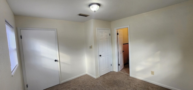 unfurnished bedroom with carpet floors, visible vents, and baseboards