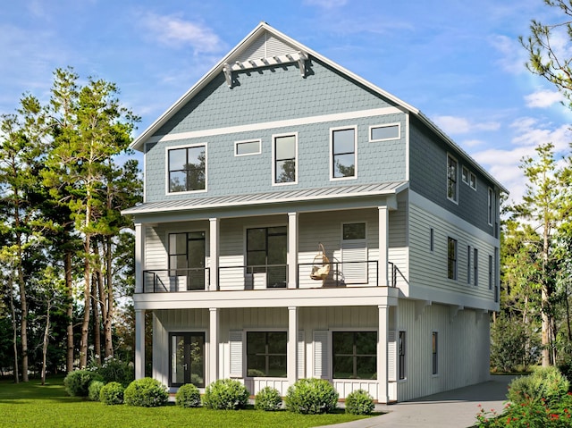 view of front of home featuring metal roof, a front lawn, a standing seam roof, and a balcony