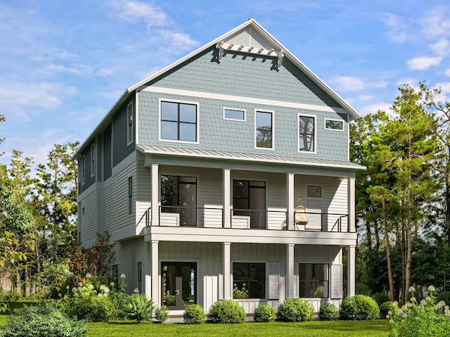 view of front facade featuring metal roof, a balcony, french doors, a standing seam roof, and a front yard