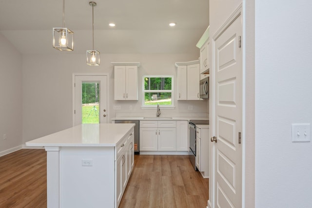 kitchen featuring a kitchen island, appliances with stainless steel finishes, a sink, and light wood-style flooring