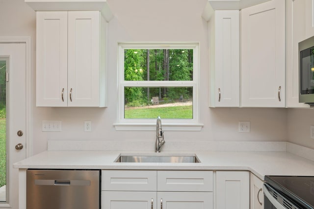 kitchen featuring a sink, appliances with stainless steel finishes, white cabinets, and light countertops