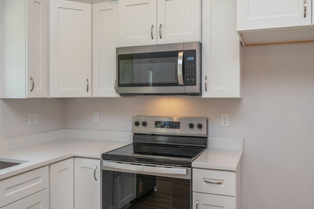 kitchen with light countertops, appliances with stainless steel finishes, and white cabinetry