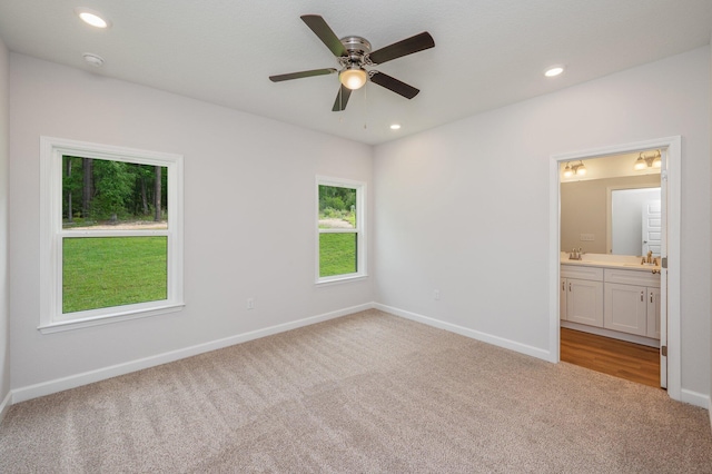 unfurnished bedroom with baseboards, a sink, carpet, and ensuite bath