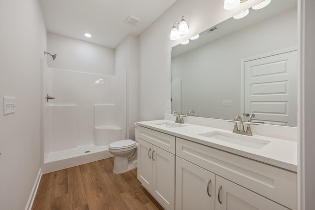 bathroom featuring a sink, walk in shower, wood finished floors, and toilet