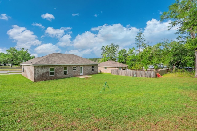 rear view of house with fence and a lawn