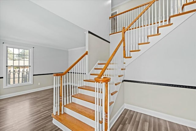 stairway with ornamental molding, baseboards, and wood finished floors