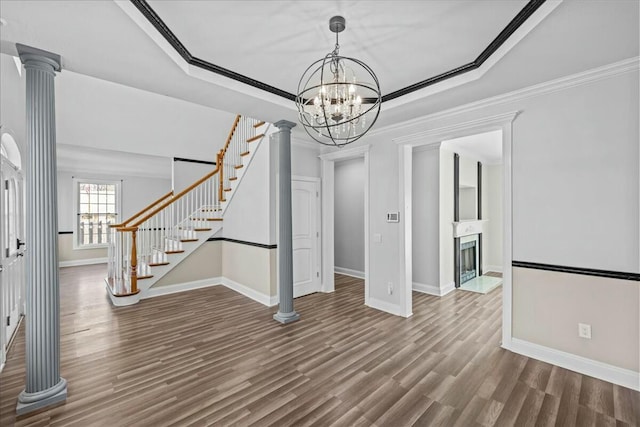 interior space with decorative columns, stairway, a raised ceiling, and wood finished floors