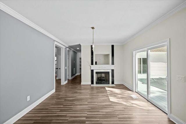 unfurnished living room featuring wood finished floors, ornamental molding, a fireplace with flush hearth, and baseboards