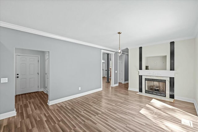 unfurnished living room featuring ornamental molding, a premium fireplace, wood finished floors, and baseboards