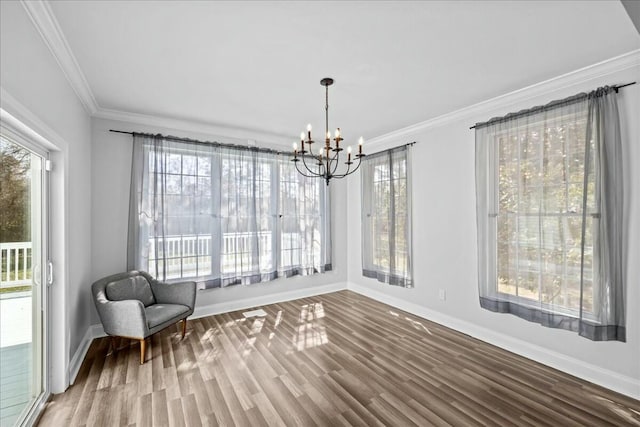 interior space featuring a notable chandelier, wood finished floors, a wealth of natural light, and crown molding