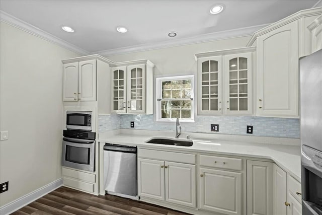 kitchen with tasteful backsplash, dark wood-style floors, appliances with stainless steel finishes, crown molding, and a sink