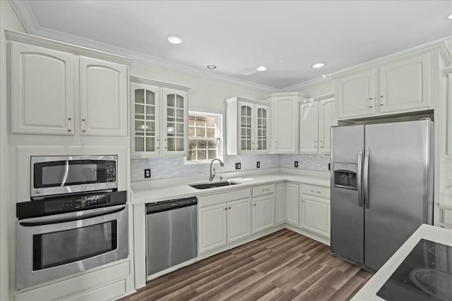 kitchen featuring tasteful backsplash, white cabinets, glass insert cabinets, stainless steel appliances, and a sink