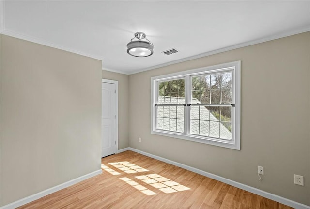 unfurnished room with crown molding, light wood-style floors, visible vents, and baseboards