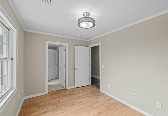 unfurnished bedroom with ornamental molding, light wood-type flooring, visible vents, and baseboards