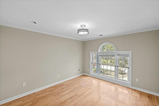 unfurnished room featuring ornamental molding, light wood finished floors, visible vents, and baseboards