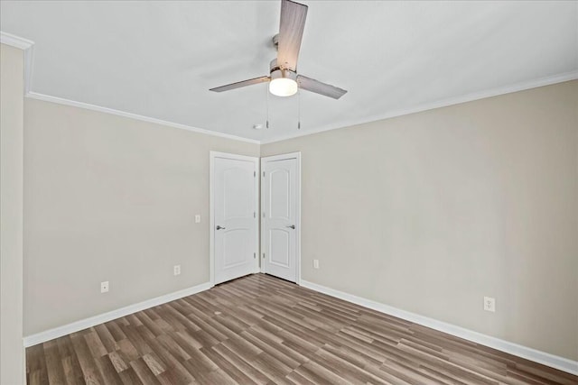 spare room featuring a ceiling fan, crown molding, baseboards, and wood finished floors