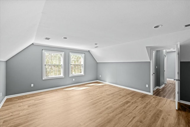 bonus room featuring lofted ceiling, wood finished floors, visible vents, and baseboards