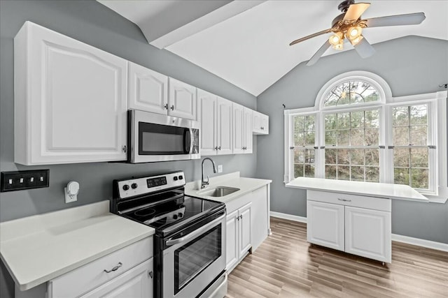 kitchen featuring lofted ceiling, a sink, white cabinets, appliances with stainless steel finishes, and light wood finished floors