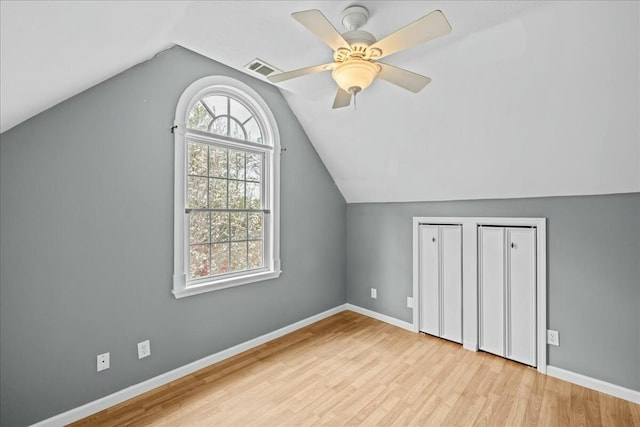 additional living space featuring lofted ceiling, visible vents, baseboards, and wood finished floors