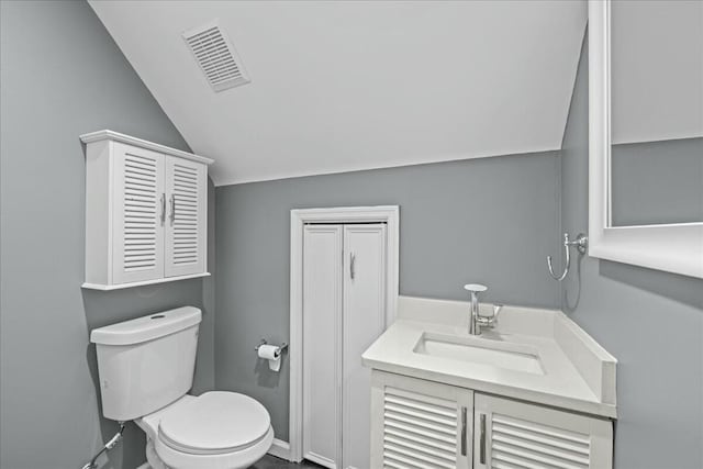 bathroom with toilet, vanity, visible vents, vaulted ceiling, and baseboards