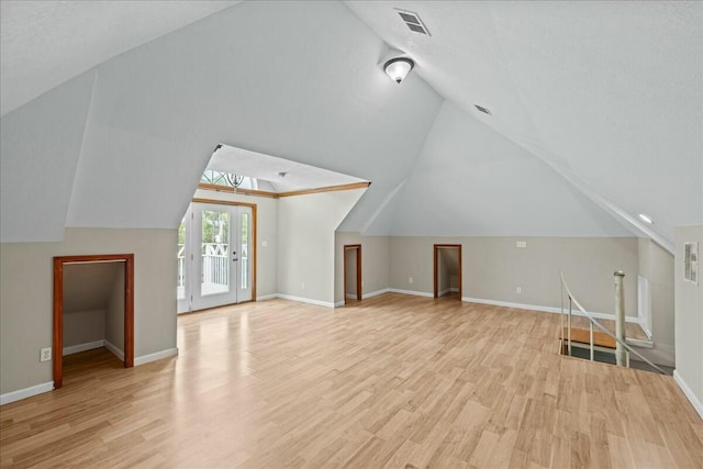 bonus room featuring light wood-type flooring, visible vents, lofted ceiling, and baseboards