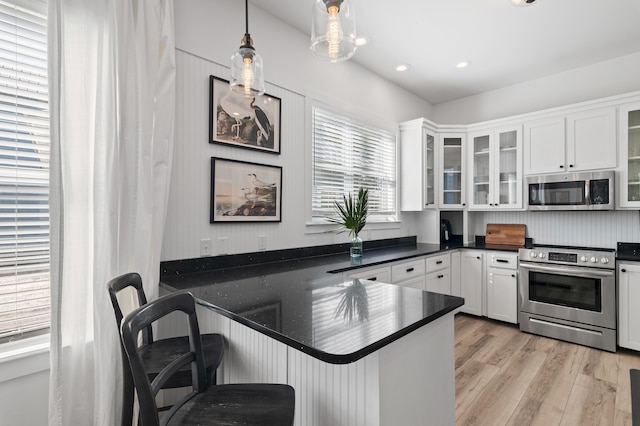 kitchen featuring dark countertops, light wood-style floors, white cabinetry, and appliances with stainless steel finishes