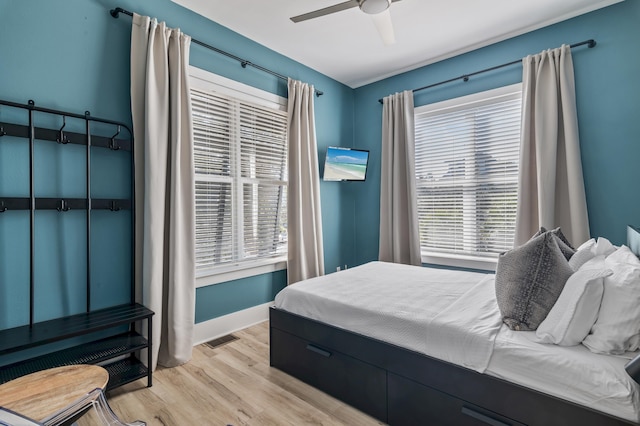 bedroom with light wood finished floors, ceiling fan, visible vents, and baseboards