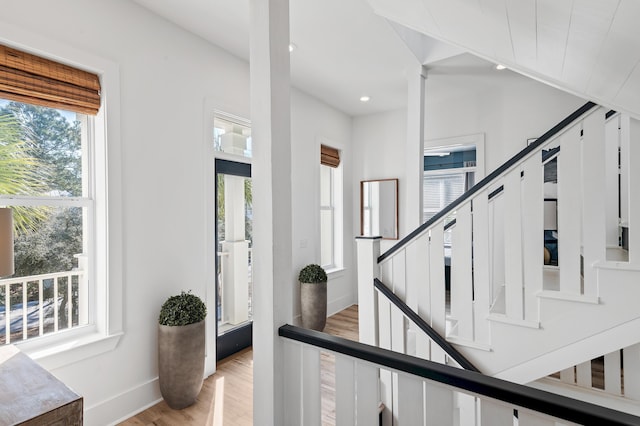 staircase featuring baseboards, vaulted ceiling, wood finished floors, and recessed lighting