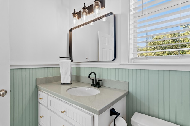 bathroom featuring toilet, a wainscoted wall, and vanity