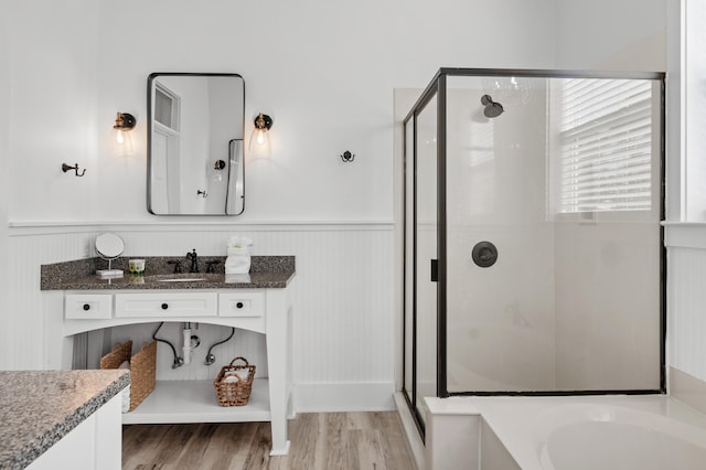 bathroom featuring a shower stall, vanity, wood finished floors, and wainscoting