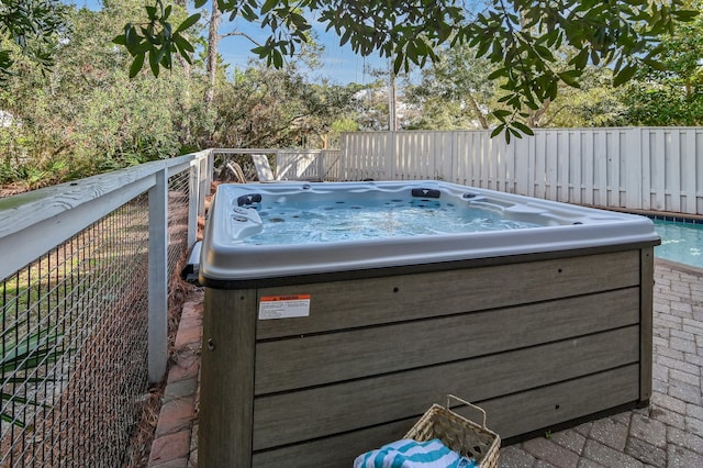 view of pool with fence and a hot tub