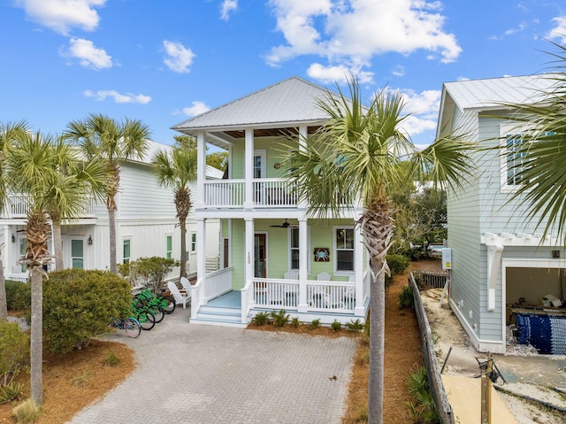 view of front of house featuring a balcony, covered porch, metal roof, and decorative driveway