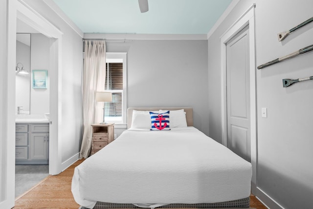 bedroom featuring wood finished floors, connected bathroom, baseboards, and ceiling fan