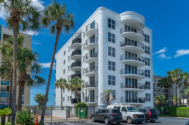 view of building exterior featuring uncovered parking and fence