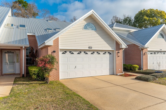 view of front of home featuring a garage, brick siding, and metal roof