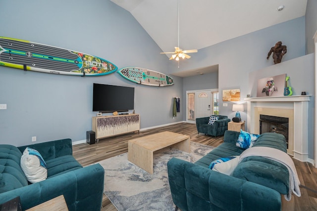 living area with high vaulted ceiling, a fireplace, wood finished floors, and baseboards