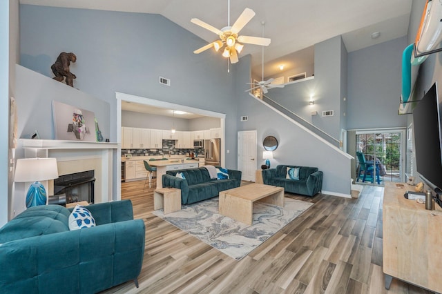 living area with stairs, visible vents, a fireplace, and wood finished floors