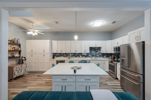 kitchen with stainless steel appliances, white cabinets, decorative light fixtures, and visible vents