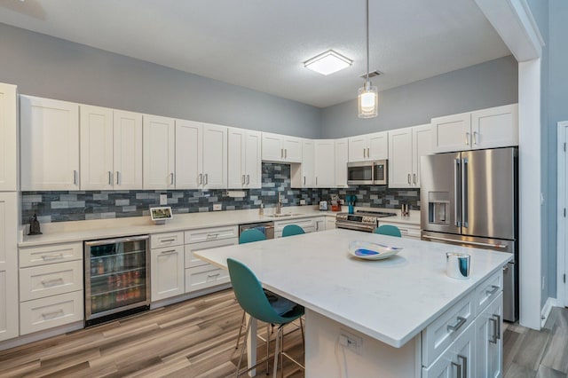 kitchen featuring hanging light fixtures, wine cooler, white cabinets, and stainless steel appliances