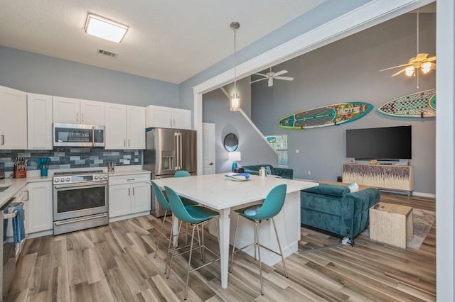 kitchen with a kitchen breakfast bar, open floor plan, light countertops, white cabinets, and high end appliances