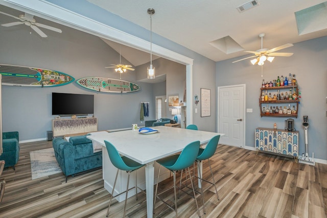 dining area featuring visible vents, vaulted ceiling, baseboards, and wood finished floors