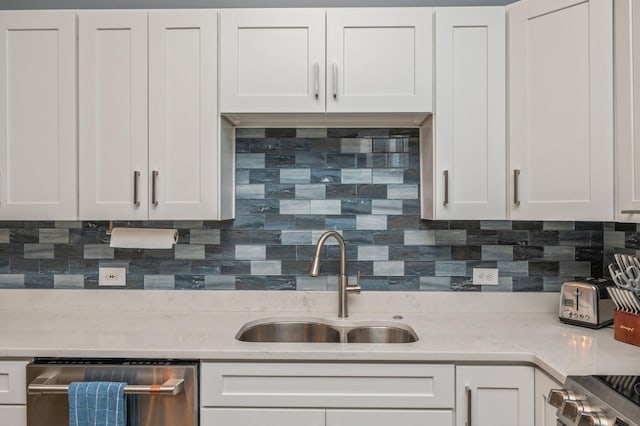 kitchen featuring decorative backsplash, white cabinetry, a sink, light stone countertops, and dishwasher