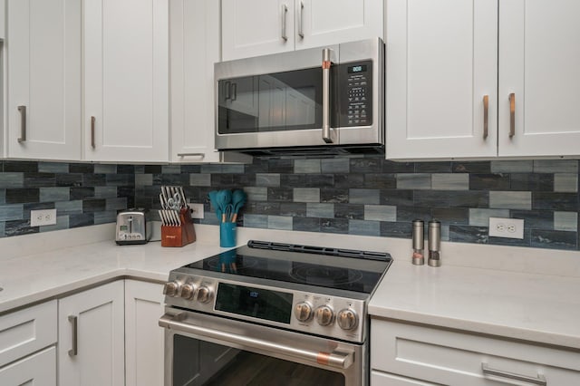 kitchen with tasteful backsplash, appliances with stainless steel finishes, light stone countertops, and white cabinets