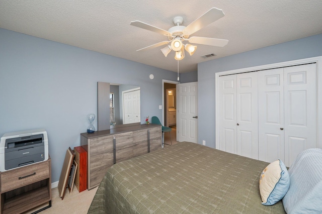 bedroom with a textured ceiling, ceiling fan, visible vents, and light colored carpet