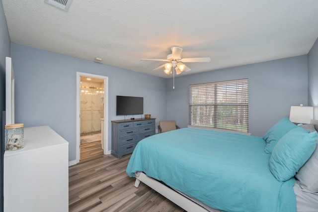 bedroom featuring visible vents, light wood-style flooring, a ceiling fan, a textured ceiling, and ensuite bath