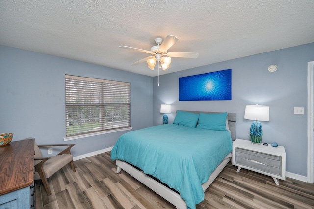 bedroom with a ceiling fan, a textured ceiling, baseboards, and wood finished floors