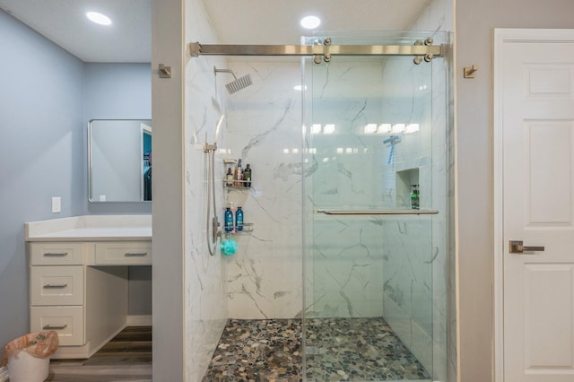 full bath with vanity, a marble finish shower, and wood finished floors