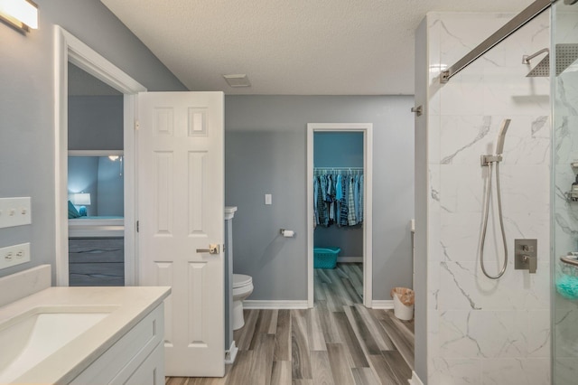 full bathroom with a textured ceiling, a marble finish shower, wood finished floors, and vanity