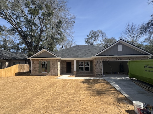 view of front facade with a garage, brick siding, a shingled roof, fence, and driveway